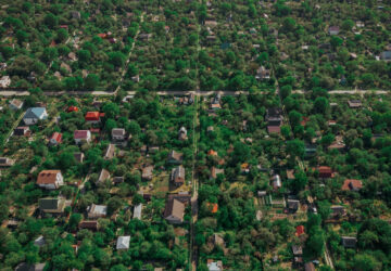 Drone image of green summer gardens with private residential developments. View of roofs of residential houses among dense green spaces in the country.